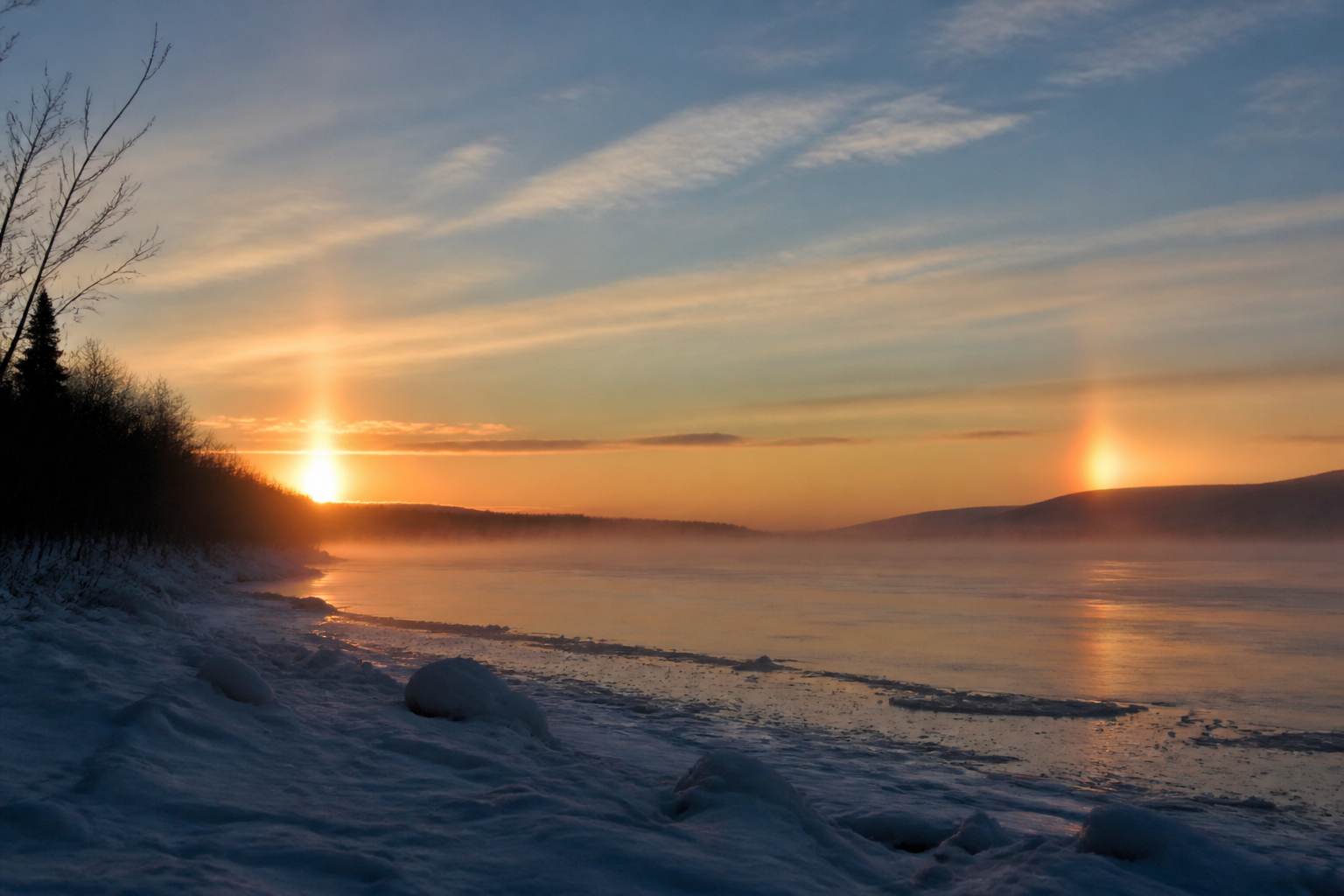 Deux faux soleils lumineux de part et d'autre du soleil bas sur l'horizon, à la même hauteur que lui