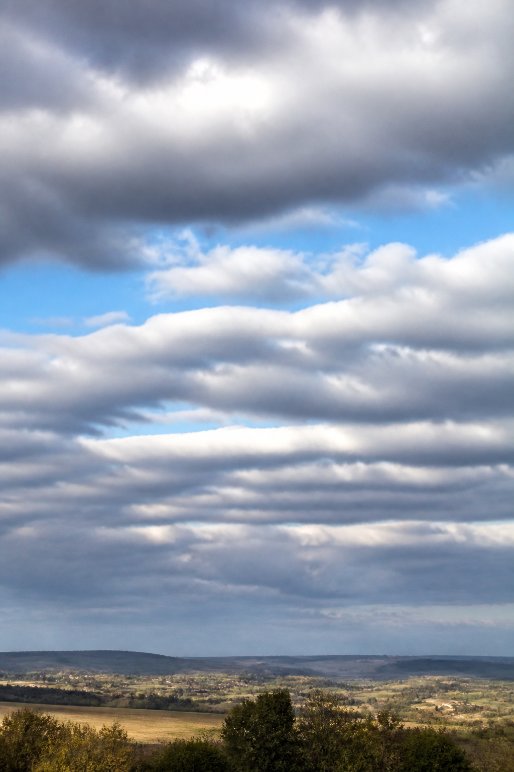 Bancs de stratocumulus en gros rouleaux gris et blancs séparés par de minces trouées de ciel bleu