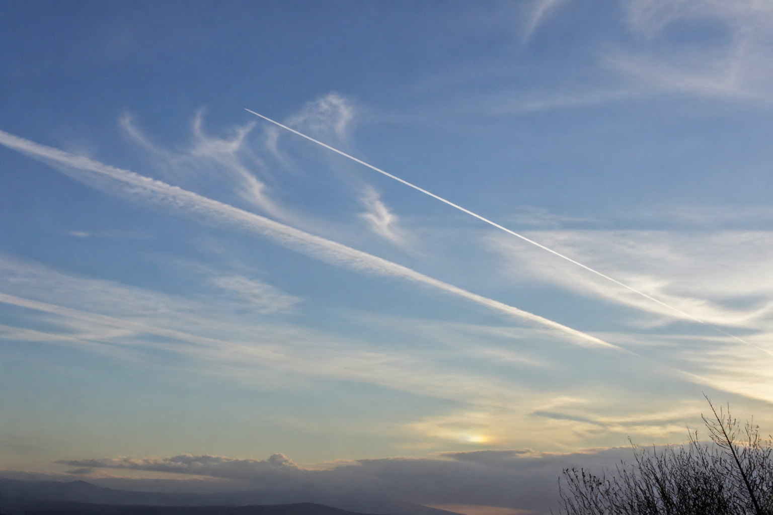 Traînées de condensation d'avions persistantes qui s'élargissent et se rejoignent en un voile de cirrus artificiel